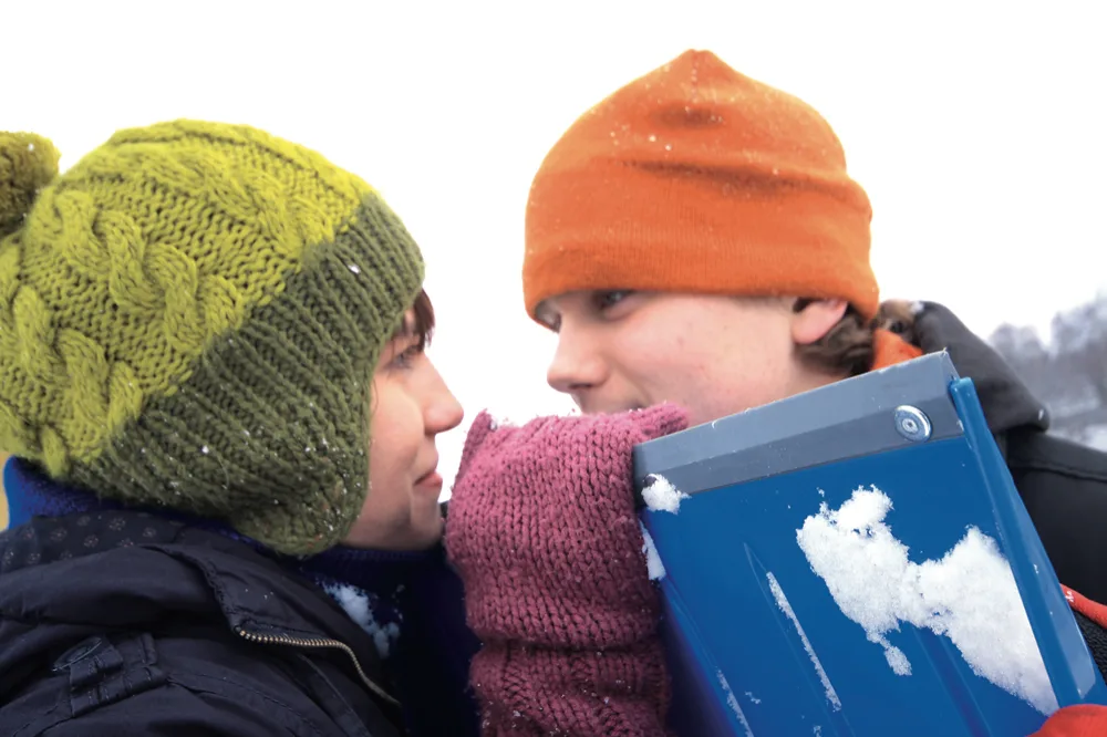 To personer ler bak en snøskuffe